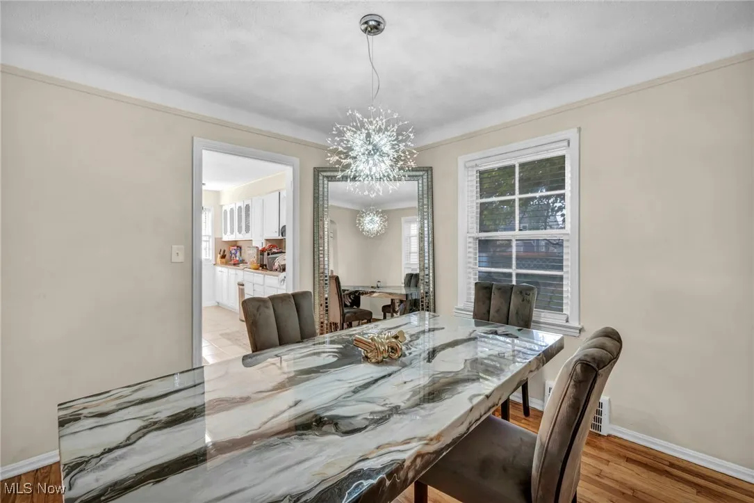 Dining space featuring a chandelier, light wood finished floors, and crown molding