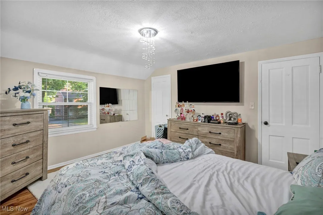 Bedroom with a textured ceiling, lofted ceiling, and wood finished floors
