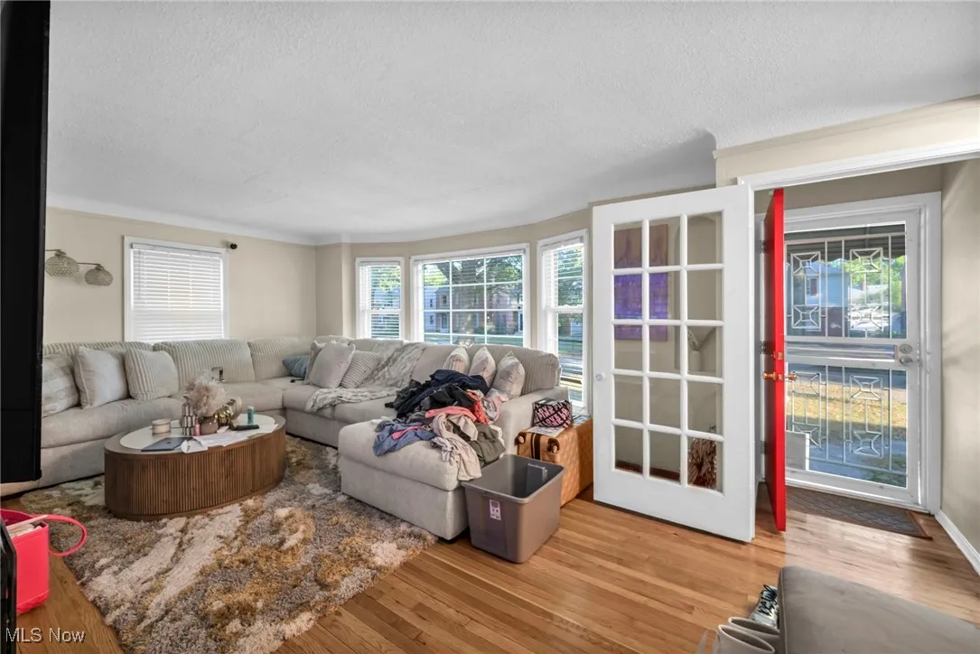 Living area with light wood-style floors, a textured ceiling, and ornamental molding