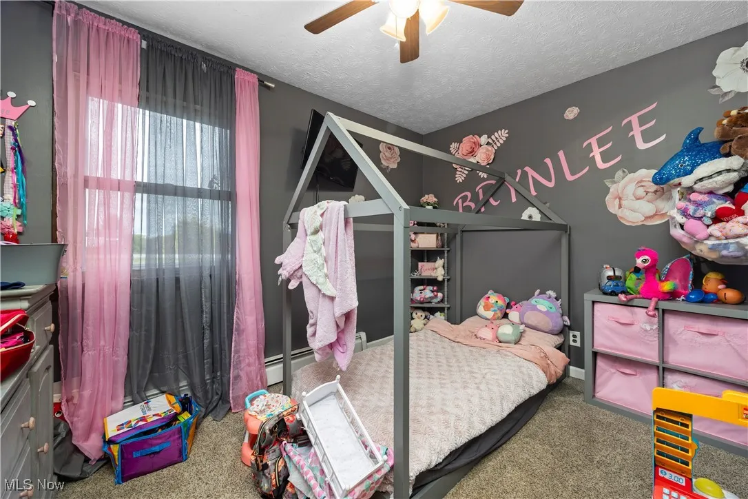 Carpeted bedroom featuring a textured ceiling, a ceiling fan, and a baseboard radiator