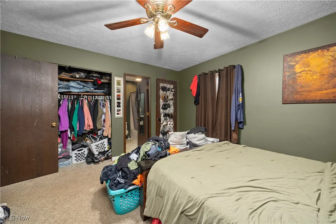 Carpeted bedroom featuring a textured ceiling, ceiling fan, and a closet