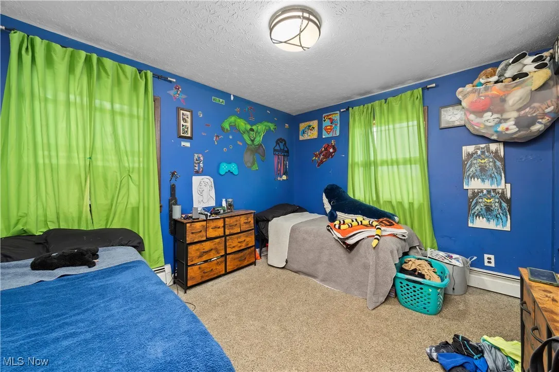 Carpeted bedroom with a textured ceiling and a baseboard heating unit