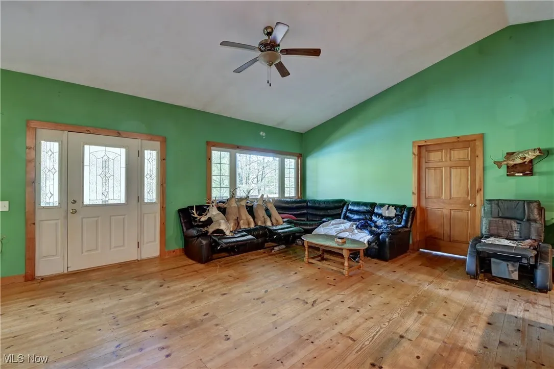 Living area featuring hardwood / wood-style floors, high vaulted ceiling, and a ceiling fan