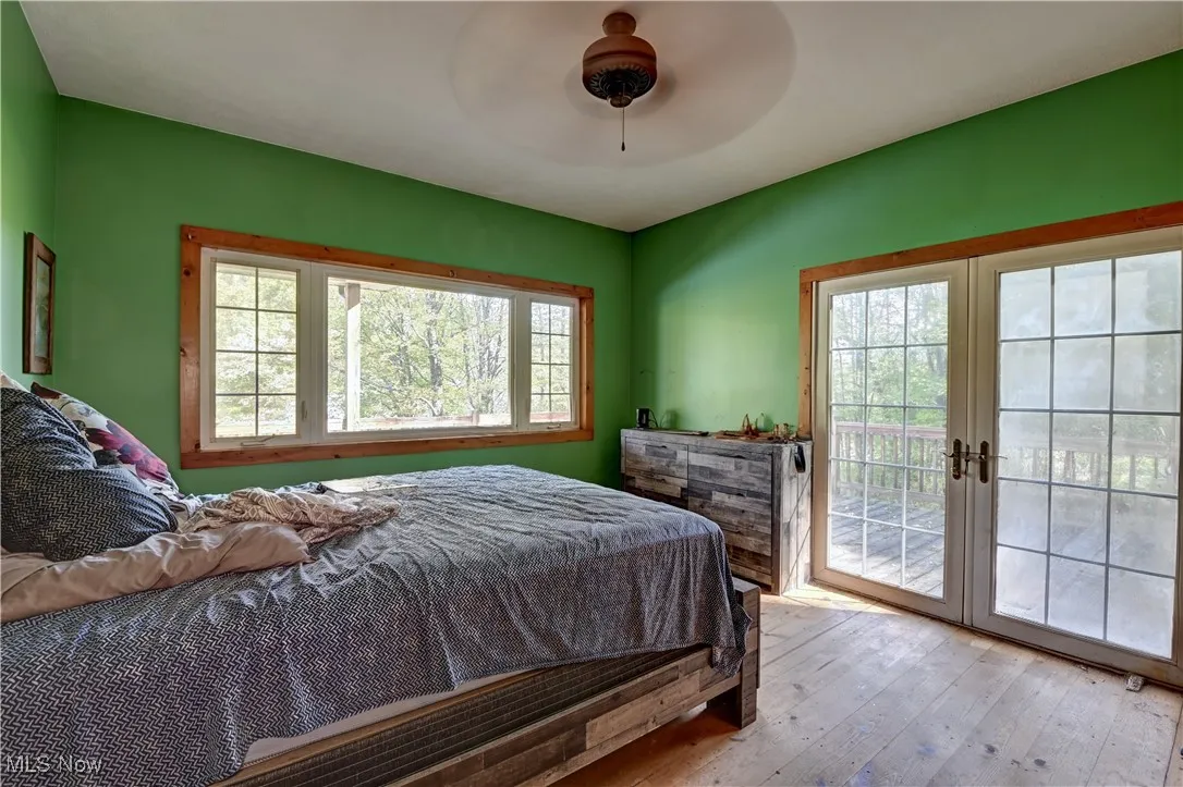 Bedroom featuring hardwood / wood-style floors, multiple windows, access to exterior, and ceiling fan