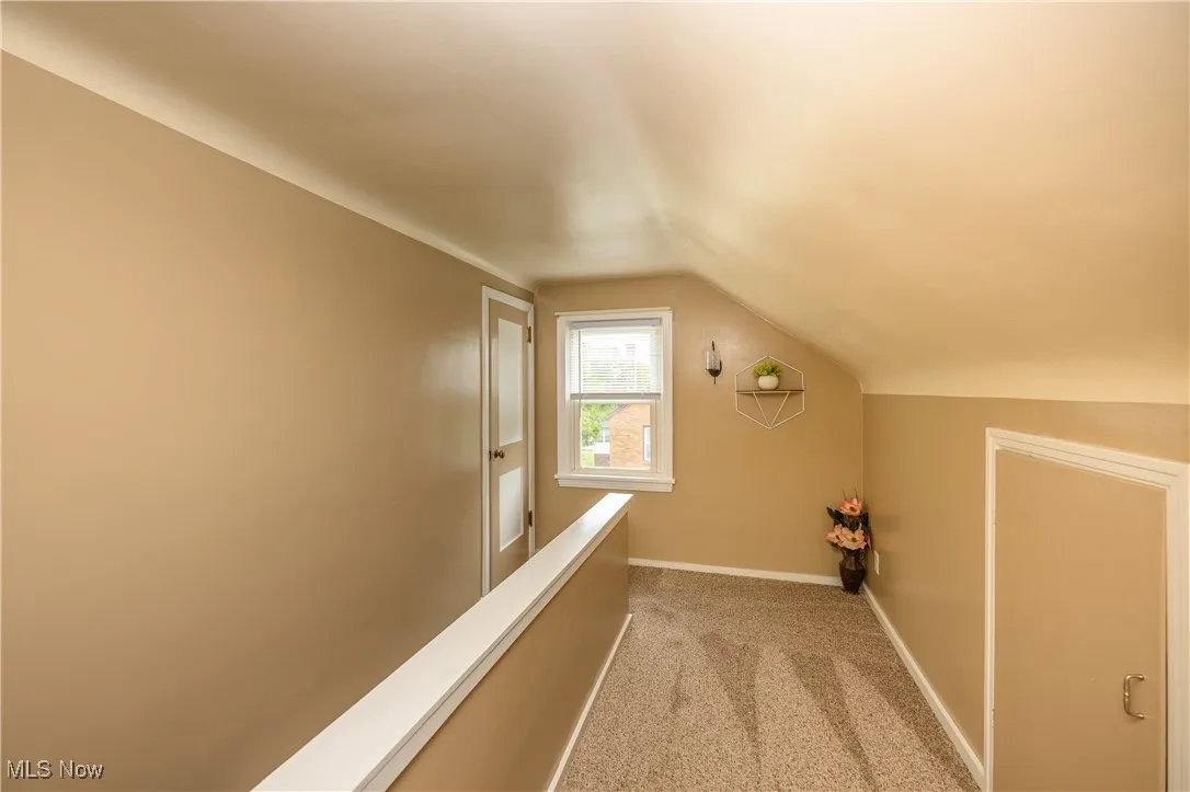 Corridor with light carpet and vaulted ceiling