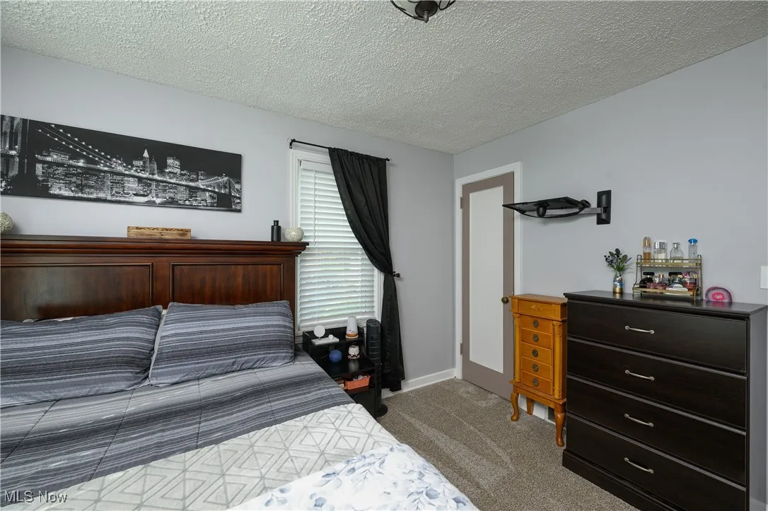 Bedroom featuring dark colored carpet and a textured ceiling