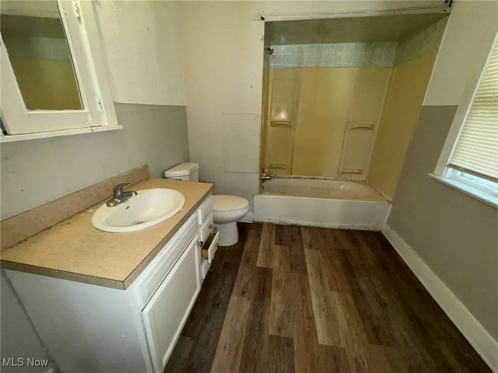 Full bath with  shower combination, dark wood-type flooring, and vanity
