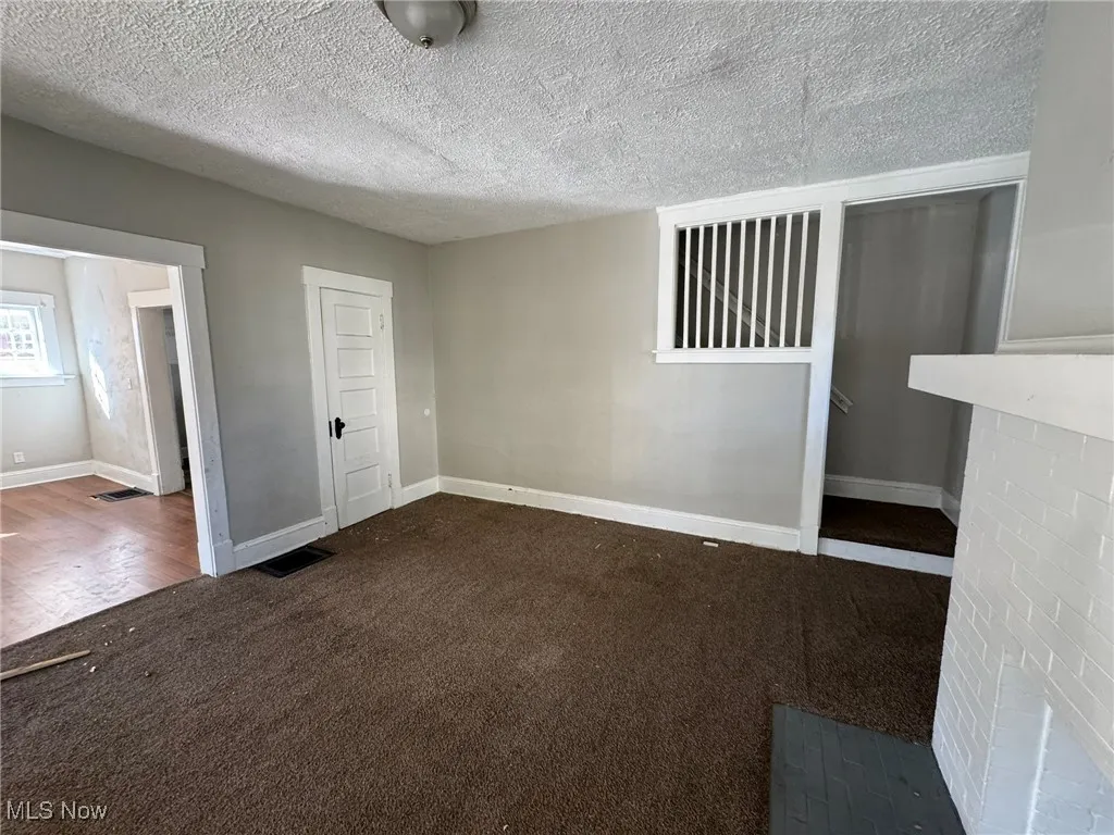 Unfurnished room with dark carpet and a textured ceiling