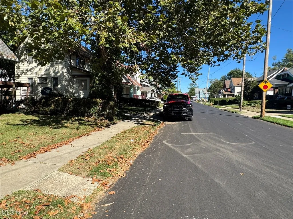 View of asphalt road with sidewalks, a residential view, curbs, and traffic signs