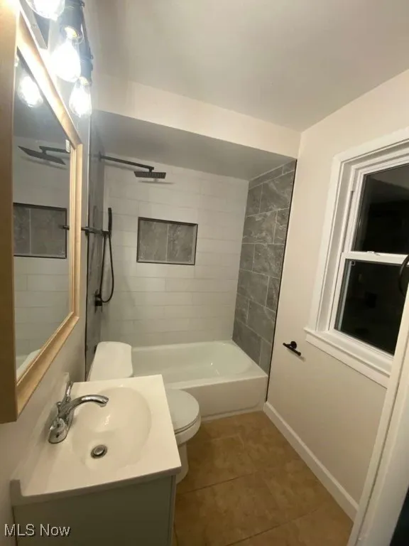 Full bath featuring vanity, light tile patterned flooring, and washtub / shower combination