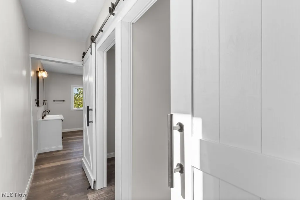 Corridor with a barn door and dark wood-type flooring