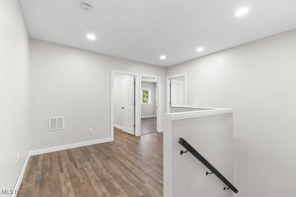 Hall featuring an upstairs landing, dark wood finished floors, and recessed lighting