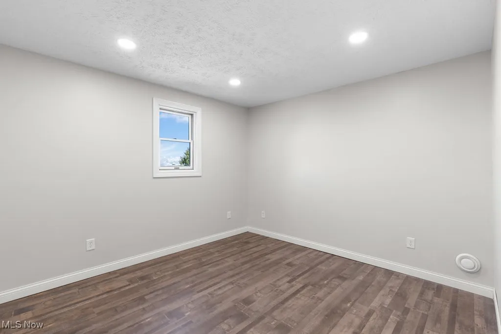Unfurnished room with a textured ceiling, dark wood finished floors, and recessed lighting