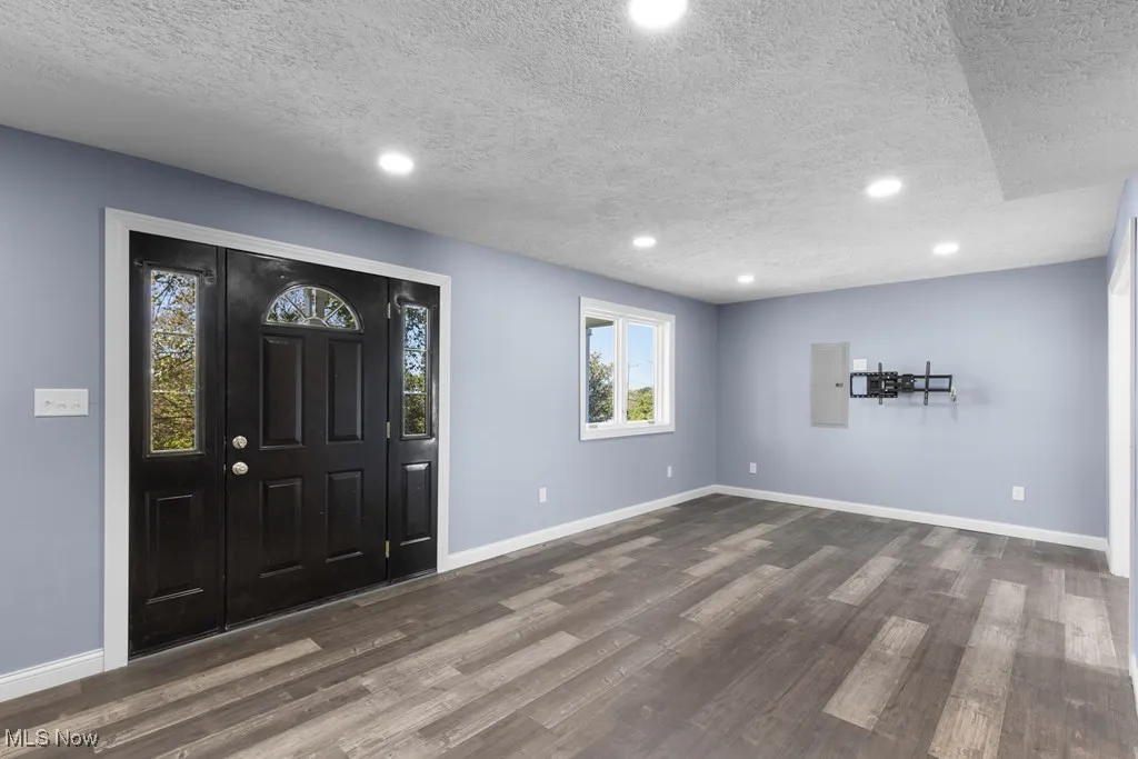 Foyer entrance featuring a textured ceiling, recessed lighting, dark wood-type flooring, and electric panel