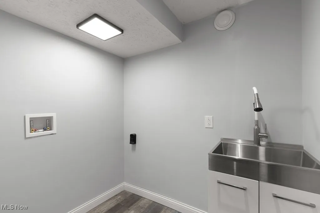 Laundry area with dark wood-style floors, a textured ceiling, and washer hookup