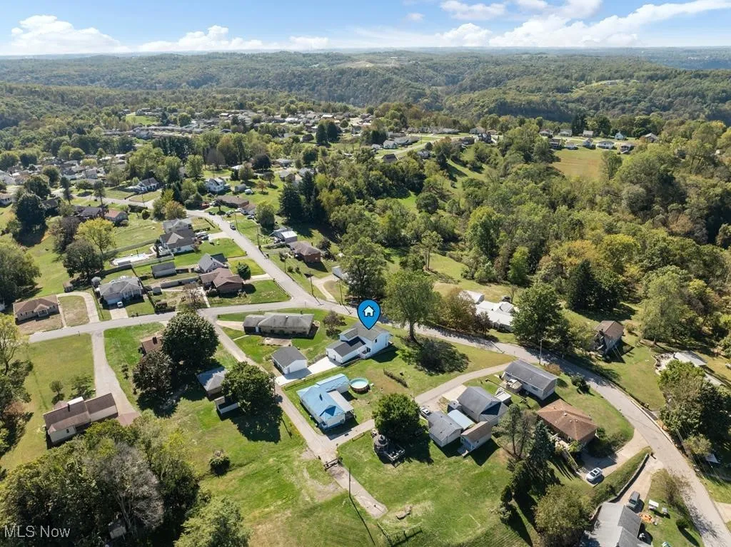 Aerial view of property and surrounding area featuring nearby suburban area