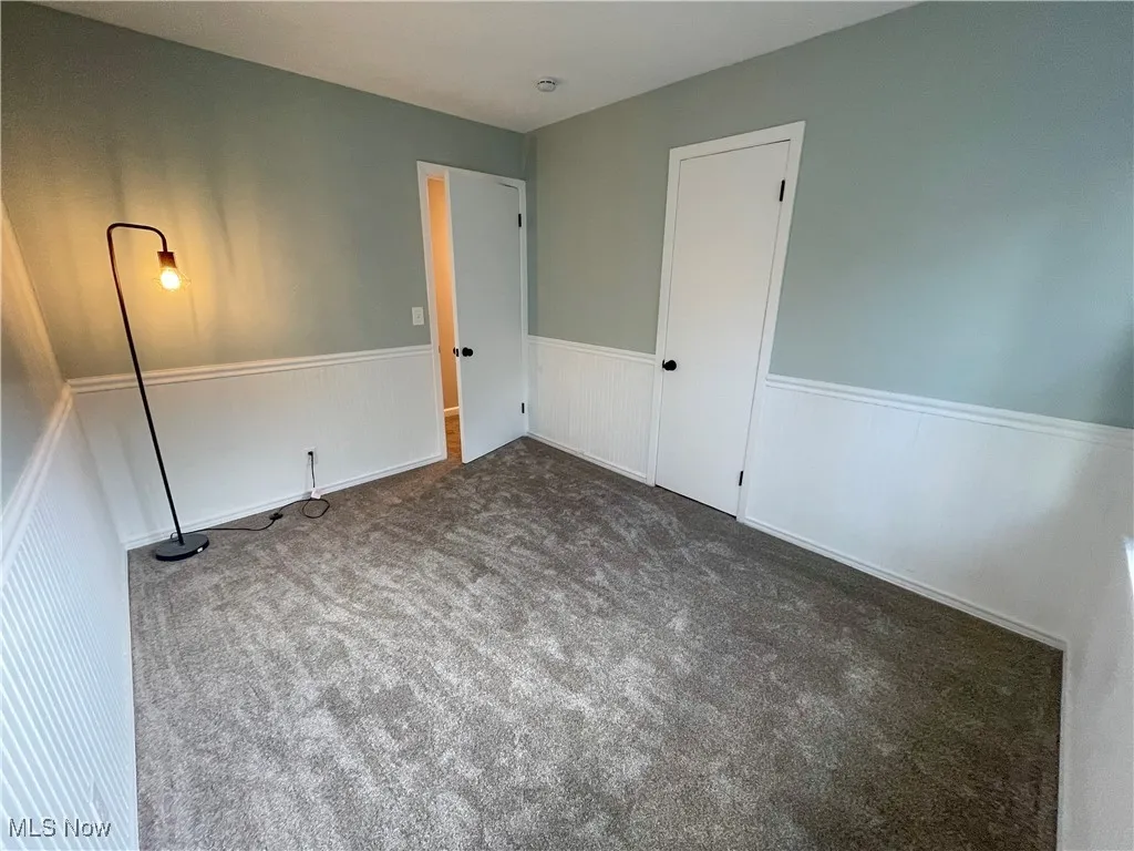 Second view of Bedroom featuring carpet floors and a wainscoted wall