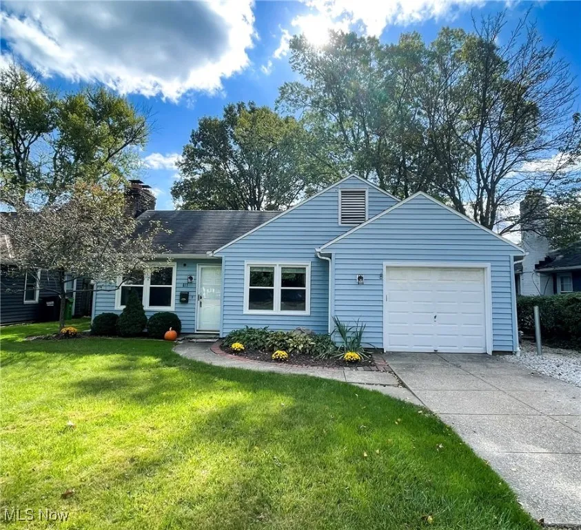 Bungalow home featuring a front yard, an attached garage, driveway, and a chimney