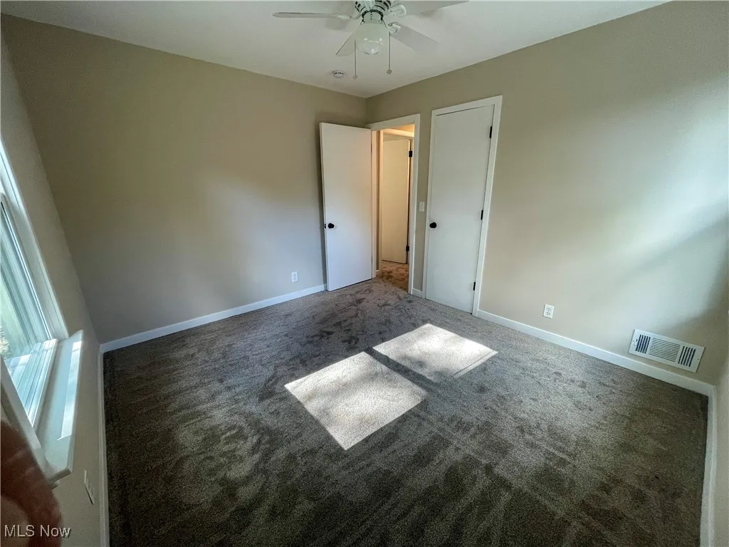 Second view bedroom with dark carpet and ceiling fan