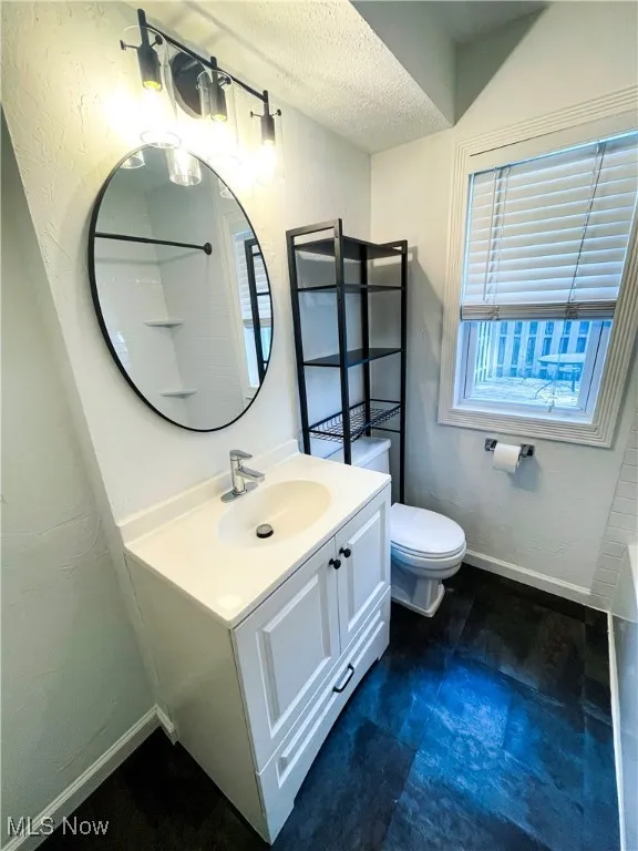 Full bathroom featuring a textured ceiling, vanity, a textured wall, and a bath