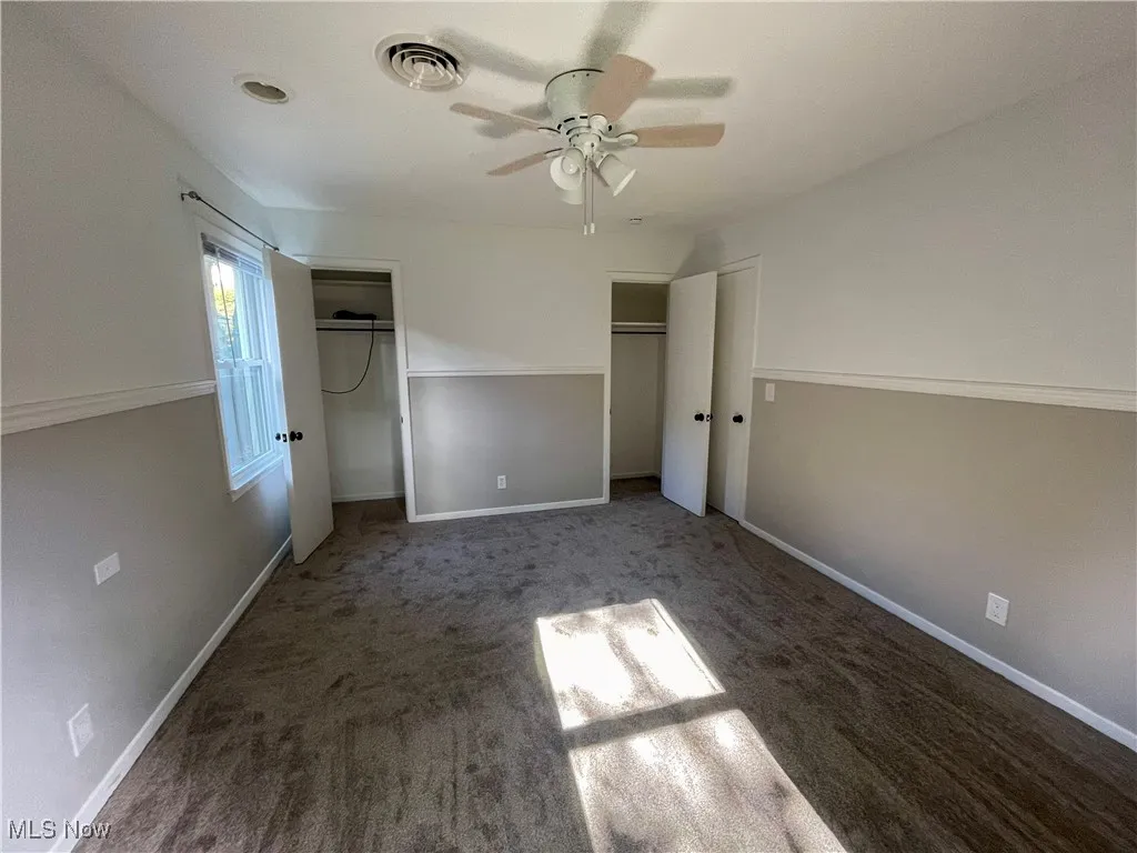 Master bedroom featuring carpet flooring, a ceiling fan, and multiple closets