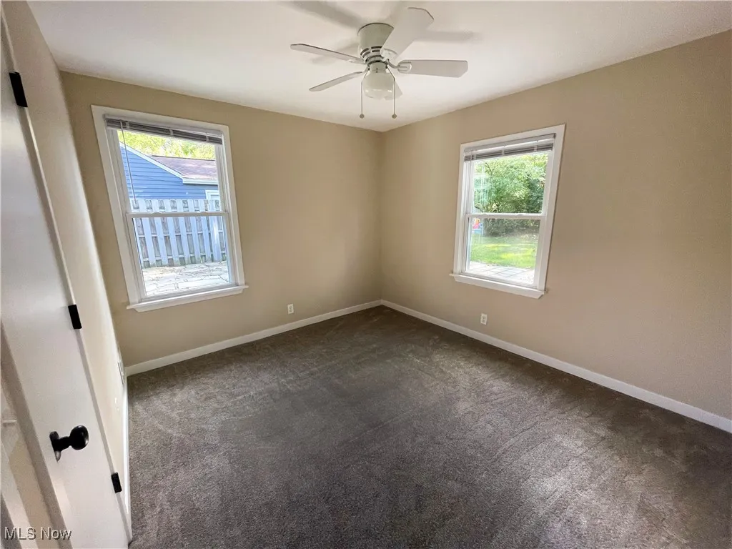 Bedroom with dark colored carpet, healthy amount of natural light, and ceiling fan