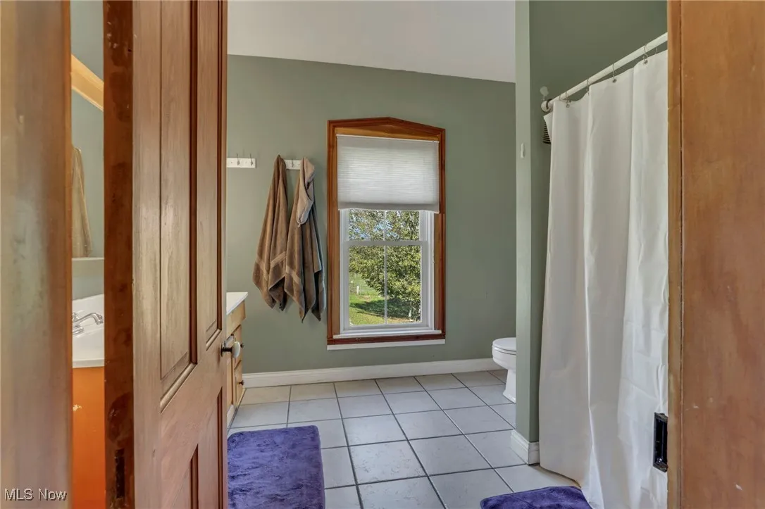 Full bath with light tile patterned floors, vanity, and a shower with curtain