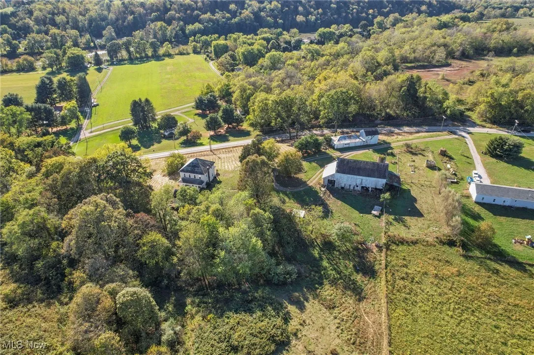 Aerial view of property and surrounding area featuring a forest