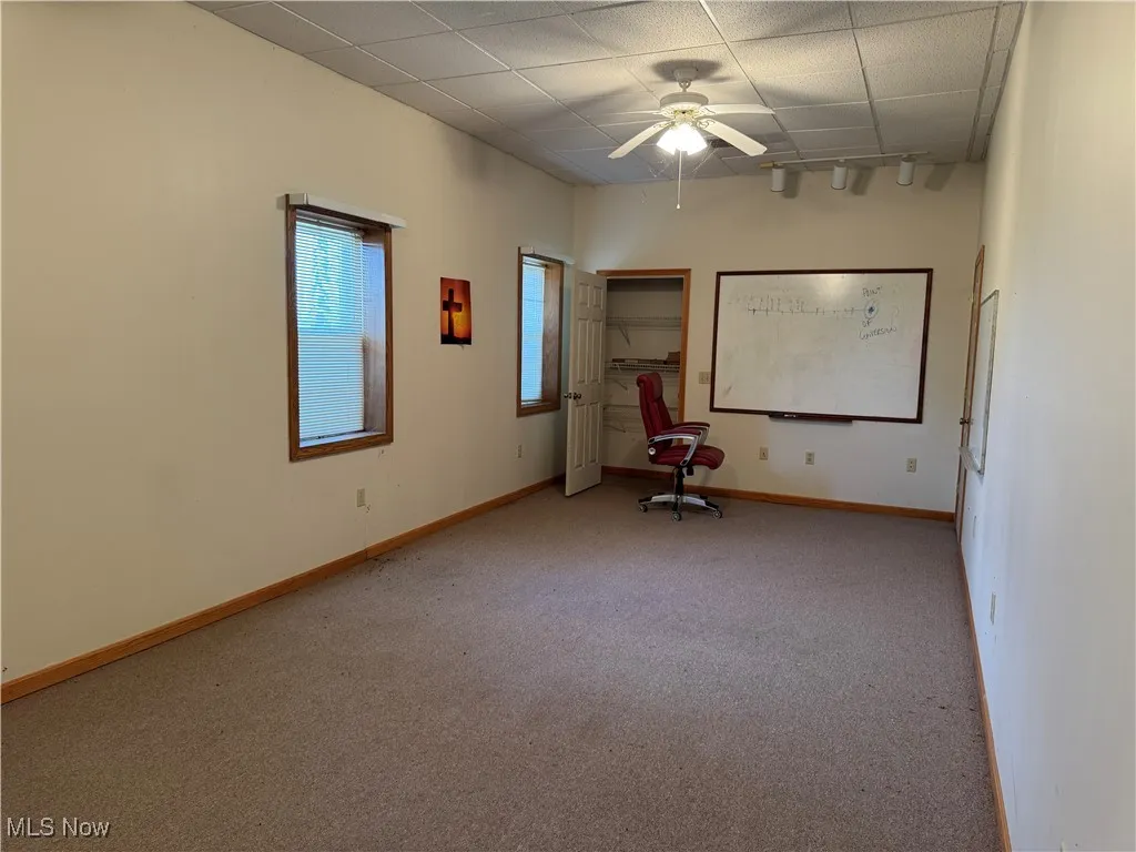 Carpeted empty room with ceiling fan and a drop ceiling