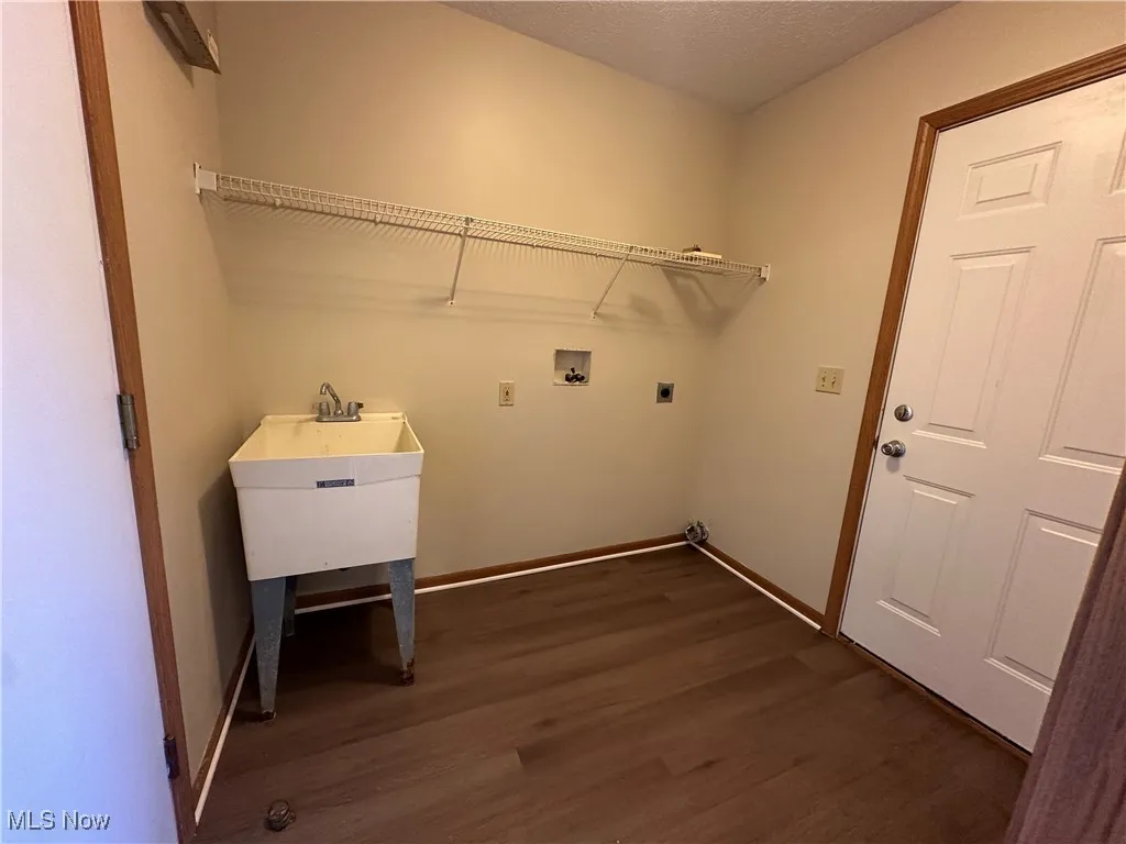 Washroom featuring dark wood-style flooring, a textured ceiling, washer hookup, and hookup for an electric dryer