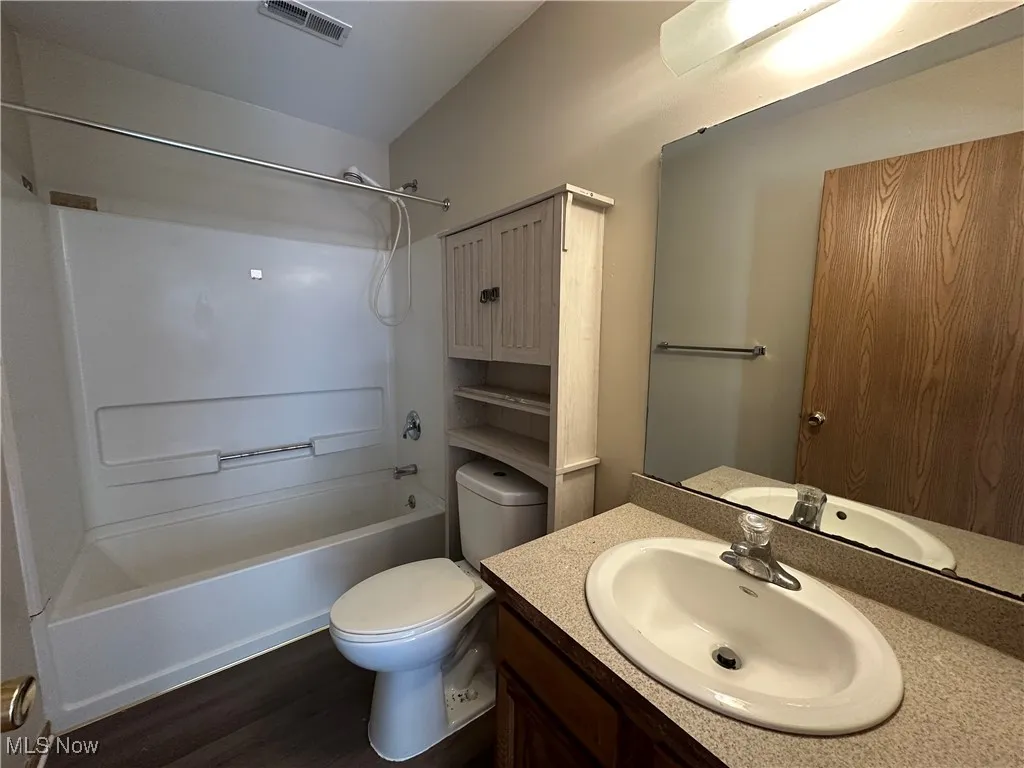 Full bathroom featuring bathtub / shower combination, vanity, and dark wood finished floors