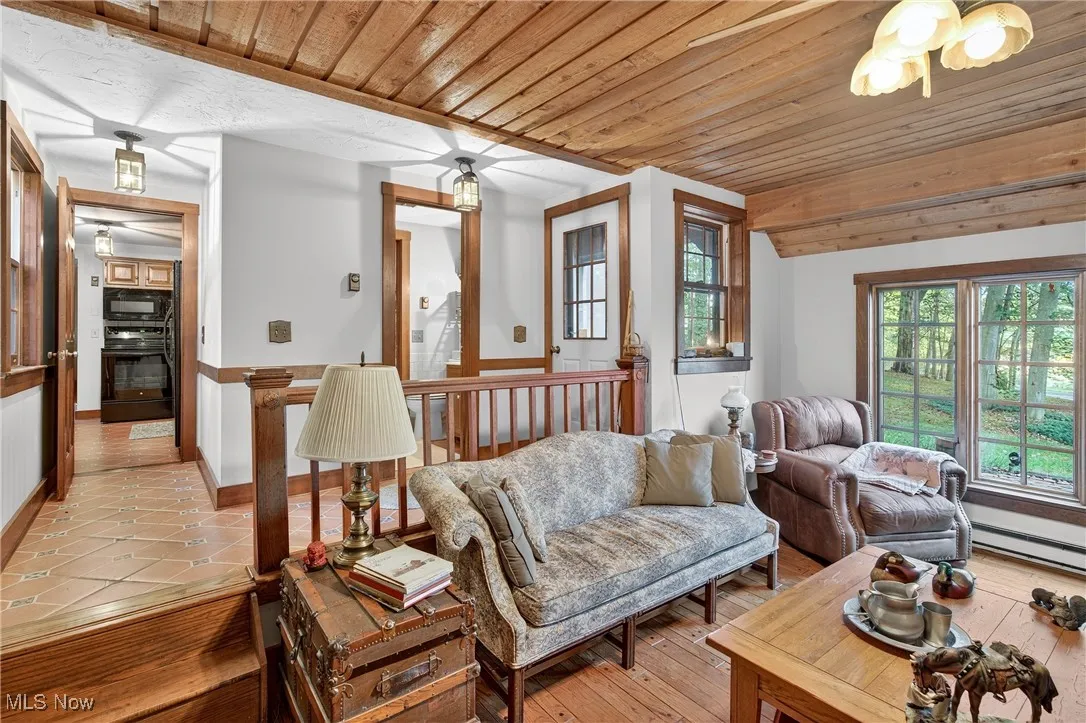 Den area featuring wooden ceiling, hardwood / wood-style flooring, and a baseboard heating unit
