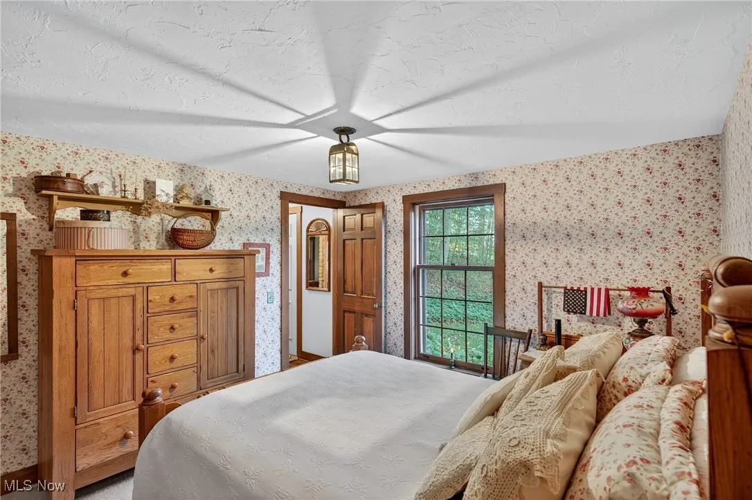 Bedroom featuring wallpapered walls and a textured ceiling