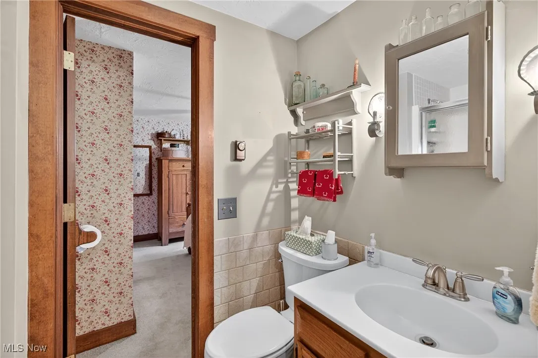 Full bathroom featuring tile walls, vanity, and a wainscoted wall