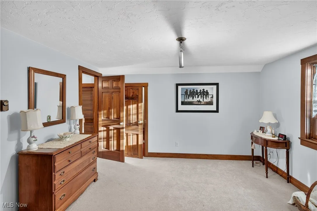 Bedroom with light carpet, a textured ceiling, and track lighting