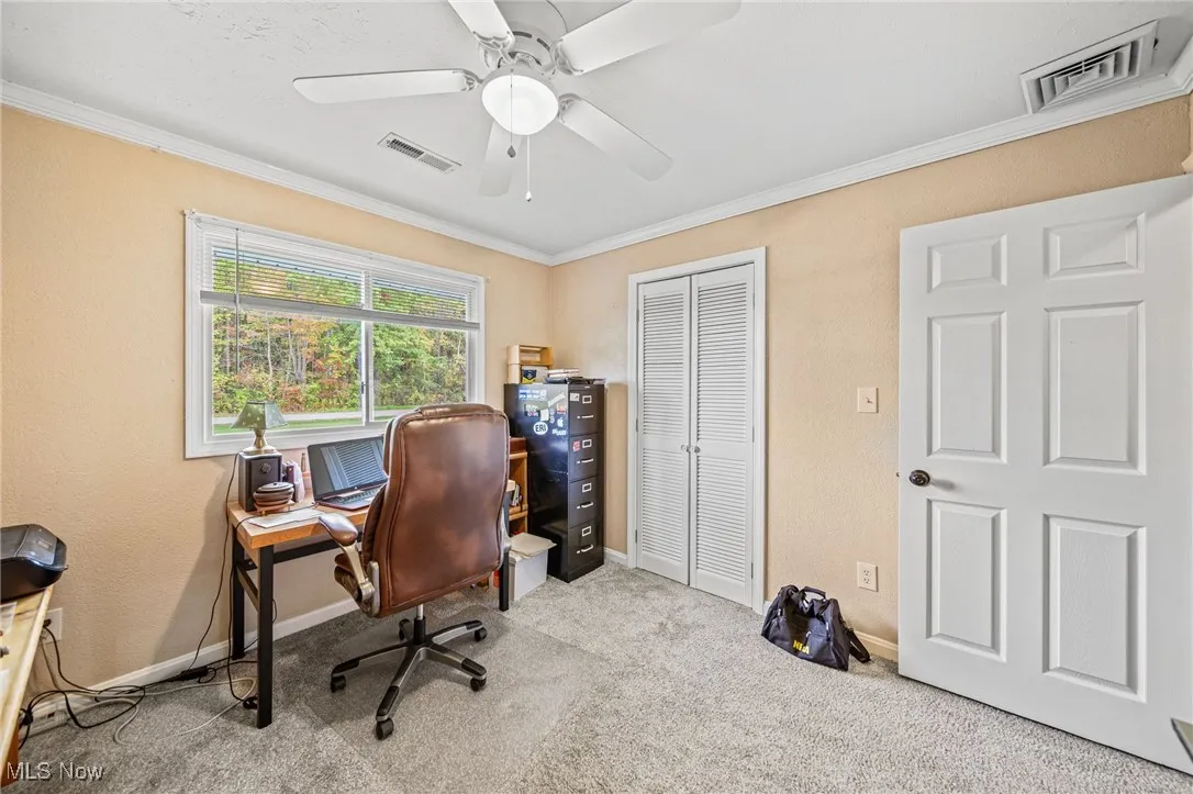 Home office with ornamental molding, light colored carpet, ceiling fan, and a textured wall