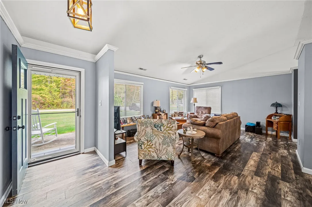 Living area with ornamental molding, dark wood-style floors, and a ceiling fan