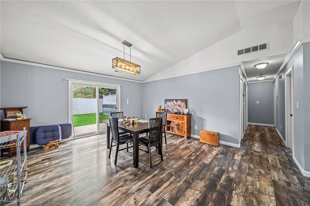 Dining space with lofted ceiling and dark wood-style flooring
