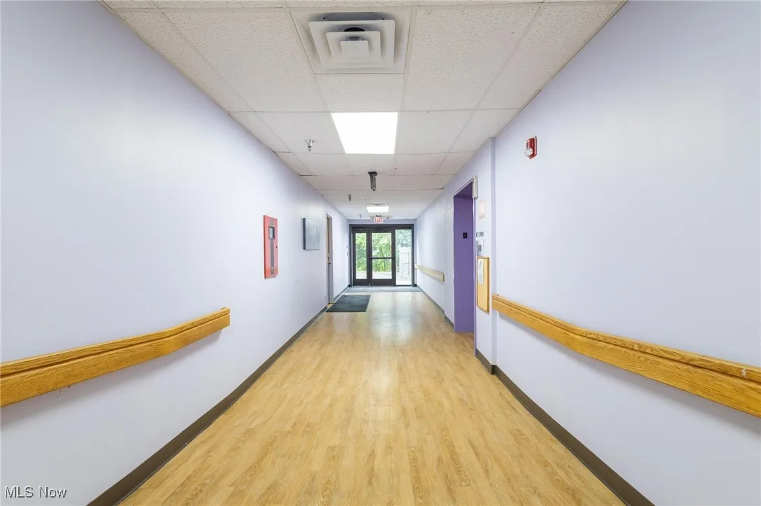 Hall with a drop ceiling, light wood-style floors, and elevator