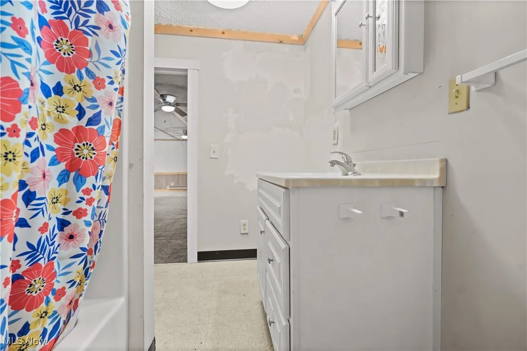 Full bathroom featuring vanity, shower / bath combination with curtain, and a textured ceiling