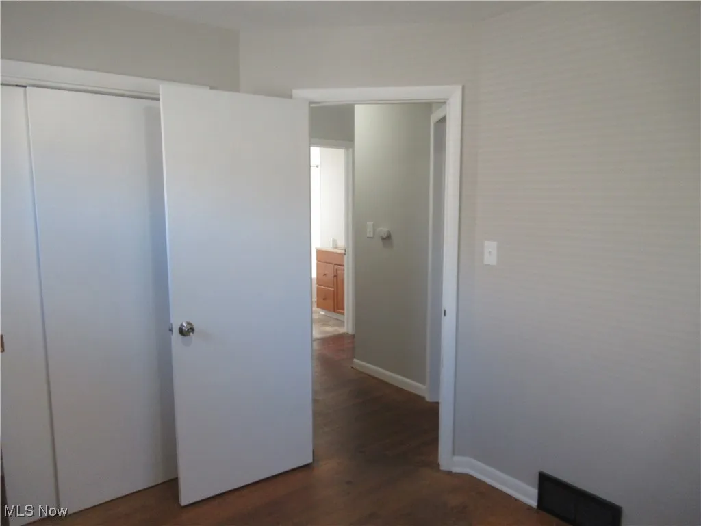 Unfurnished bedroom with dark wood-style floors and a closet