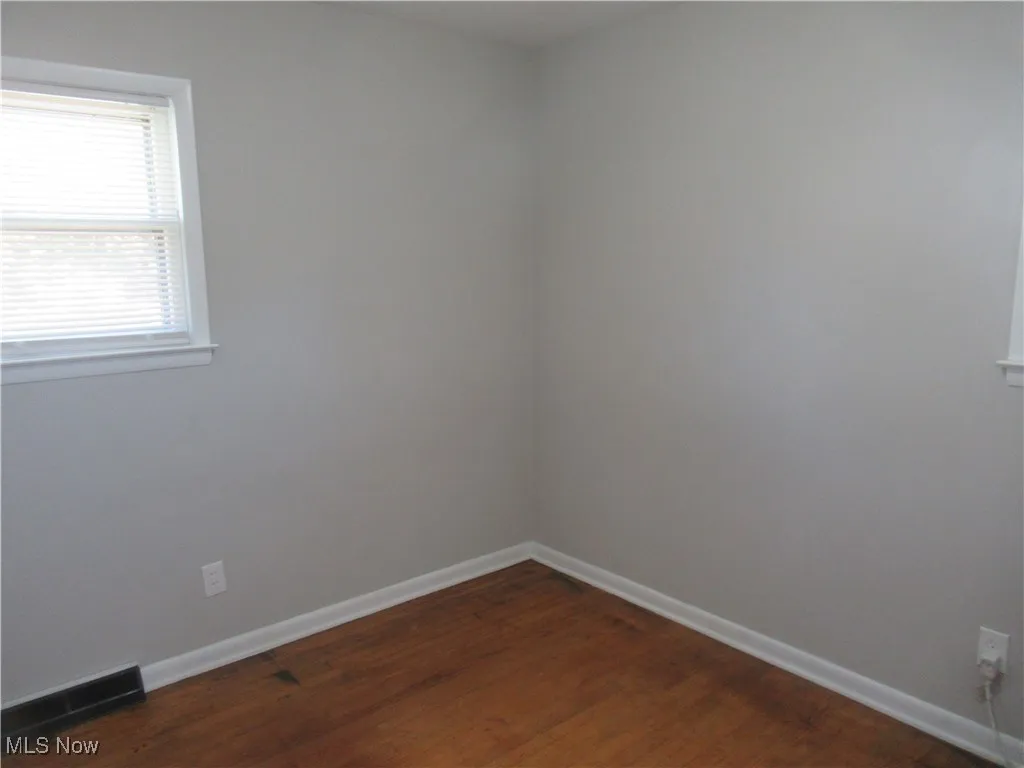 Spare room with dark wood finished floors and baseboards