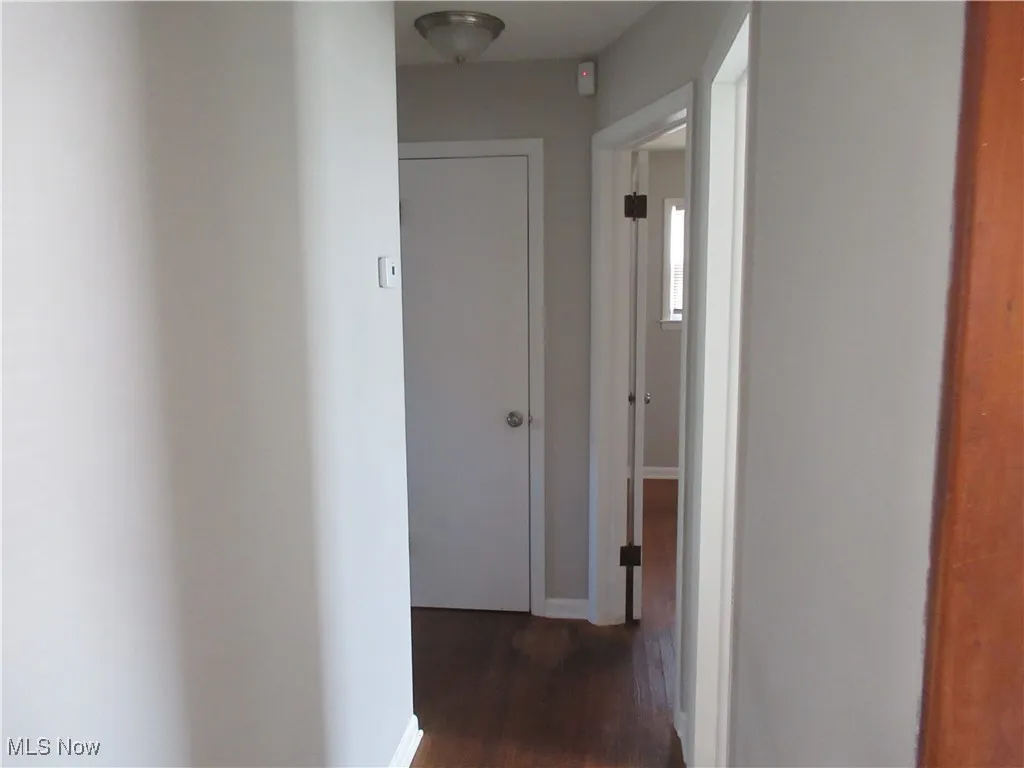 Hall featuring baseboards and dark wood-type flooring