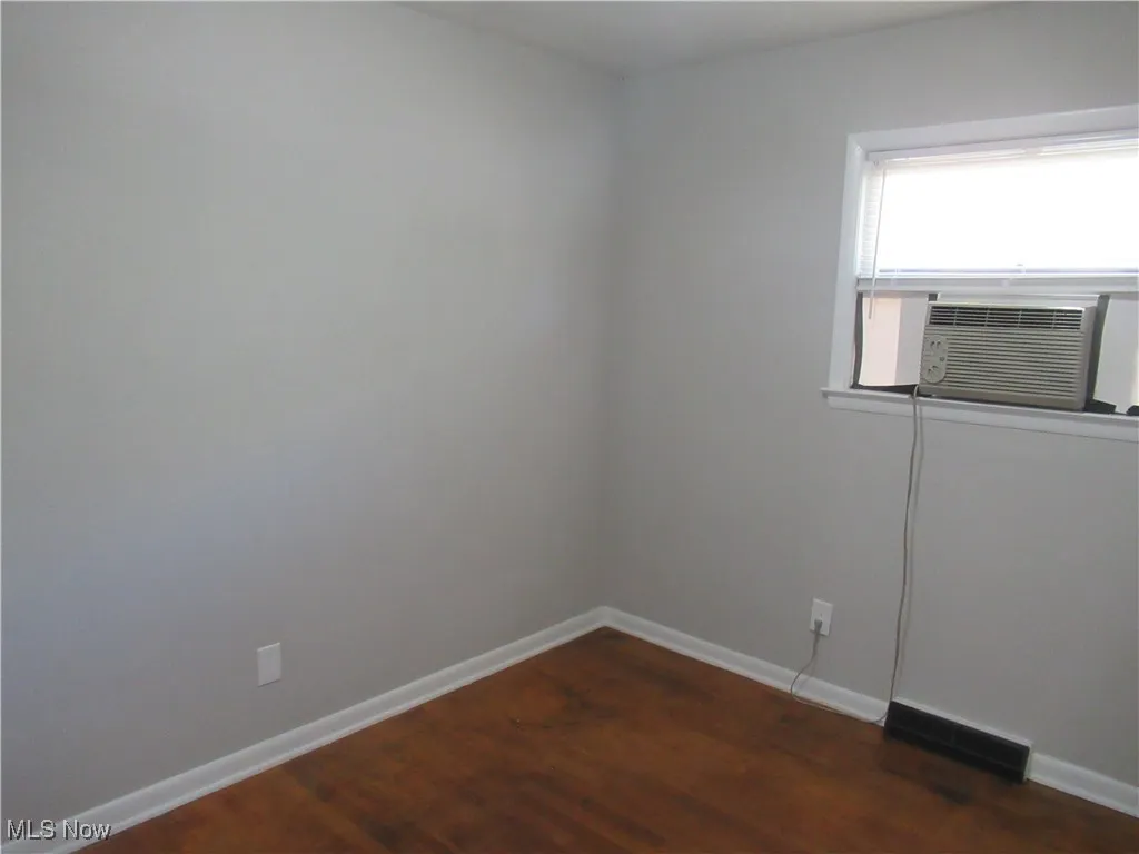 Spare room featuring dark wood-style floors and cooling unit