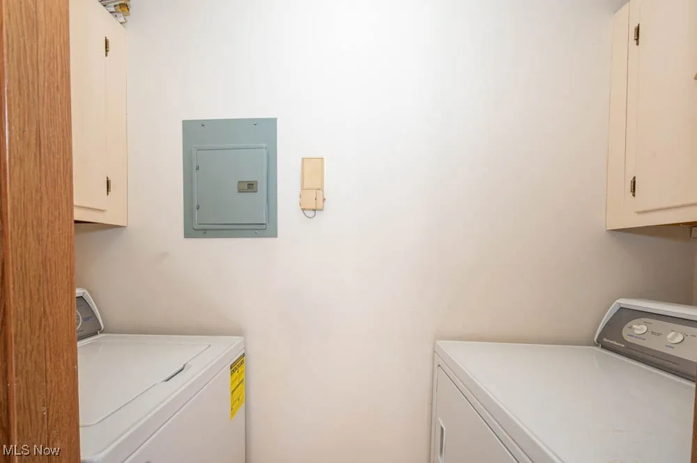 Washroom featuring cabinet space, electric panel, and independent washer and dryer