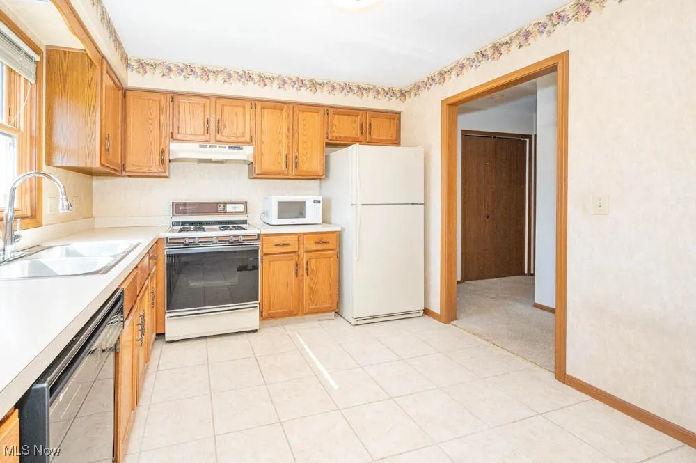 Kitchen with white appliances including gas stove, refrigerator, dishwasher, microwave and disposal.