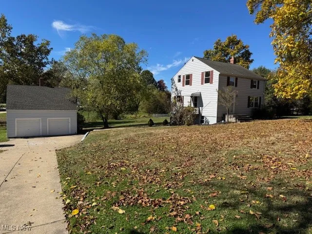 View of front of home with an outdoor structure, a chimney, a garage, a front lawn, and driveway