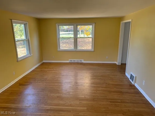 Empty room with healthy amount of natural light and light wood-style floors