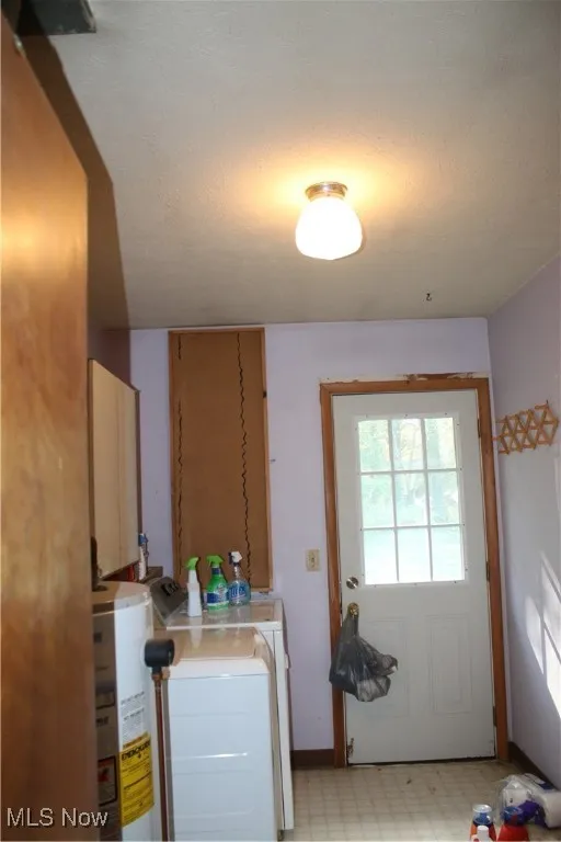 Laundry area with light floors, water heater, independent washer and dryer, and a textured ceiling