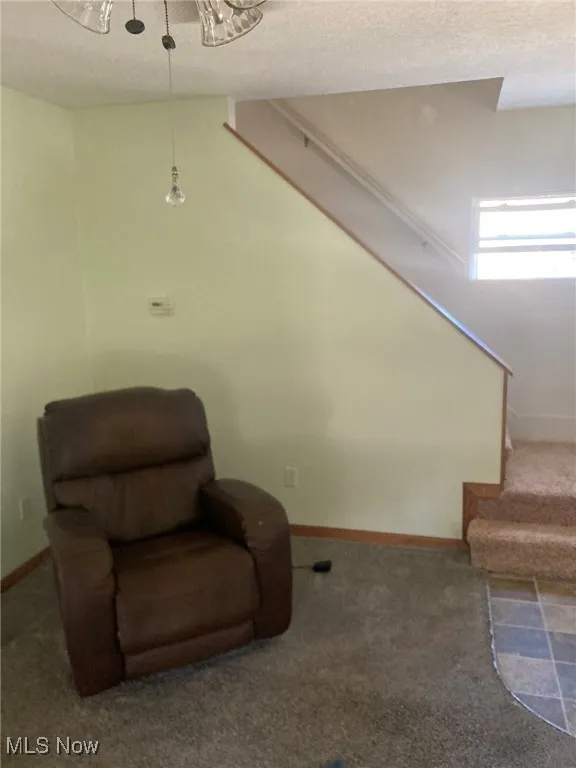 Sitting room featuring carpet floors, a textured ceiling, and stairway